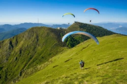 Parapendio in volo sopra i prati di Alpe Pradecolo, panorama montano