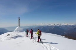 Escursionisti con ciaspole su neve in vetta, panorama di montagne lontane