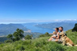 Famiglia seduta sull’erba con vista sul Lago Maggiore in giornata limpida